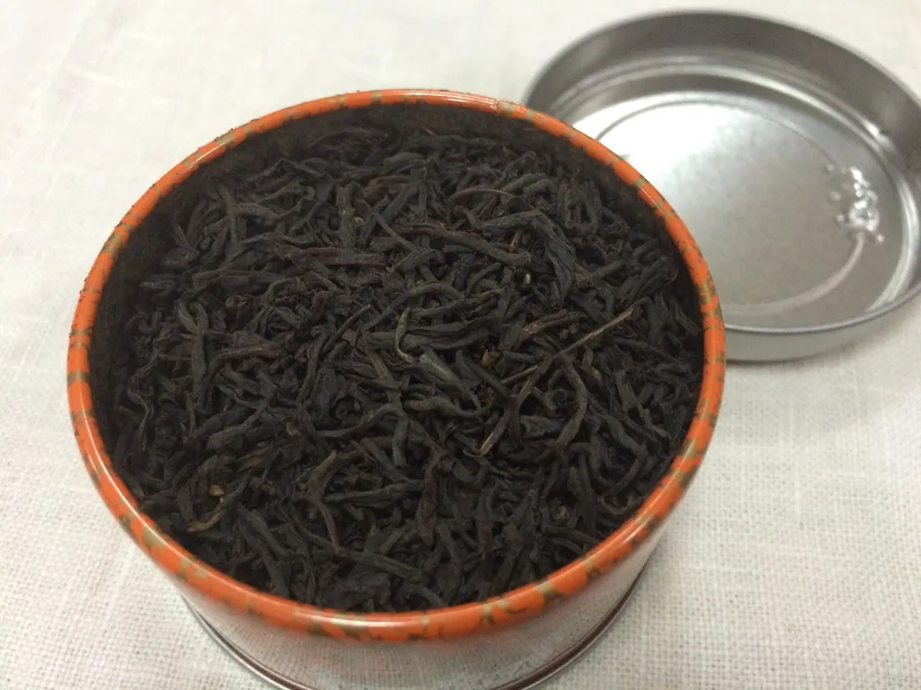 An open Kusmi Tea tin full of loose black tea.