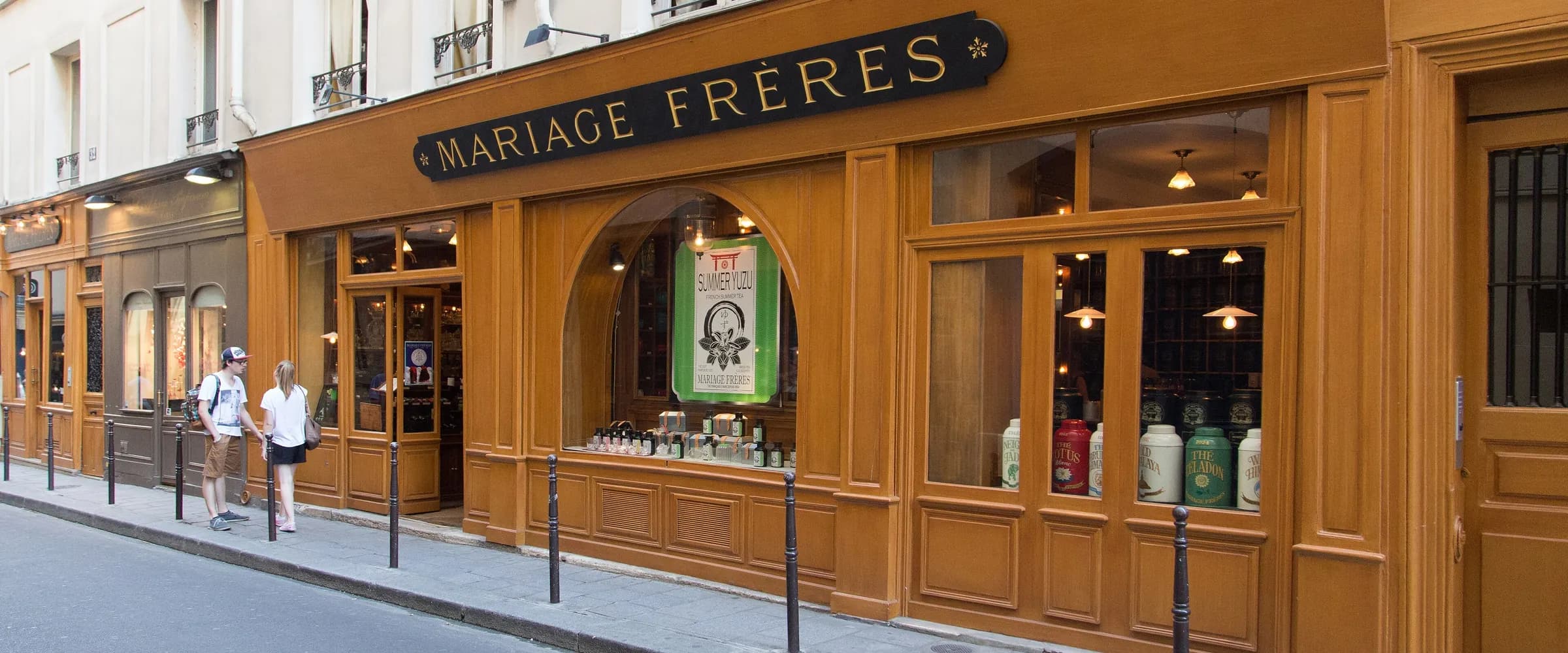 The Mariage Frères shopfront at 30 rue du Bourg-Tibourg in the Marais: honey-coloured wooden panelling, a black sign with gold letters and tea tins in the windows.