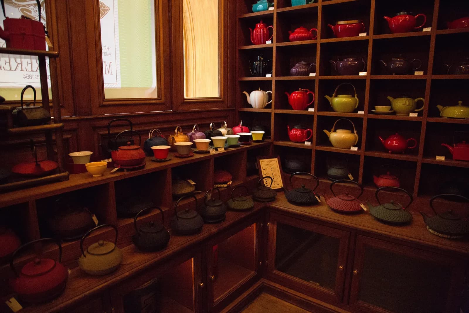 A corner of the Bourg-Tibourg shop lined with wooden shelves of cast-iron and porcelain teapots in red, black, green and cream.