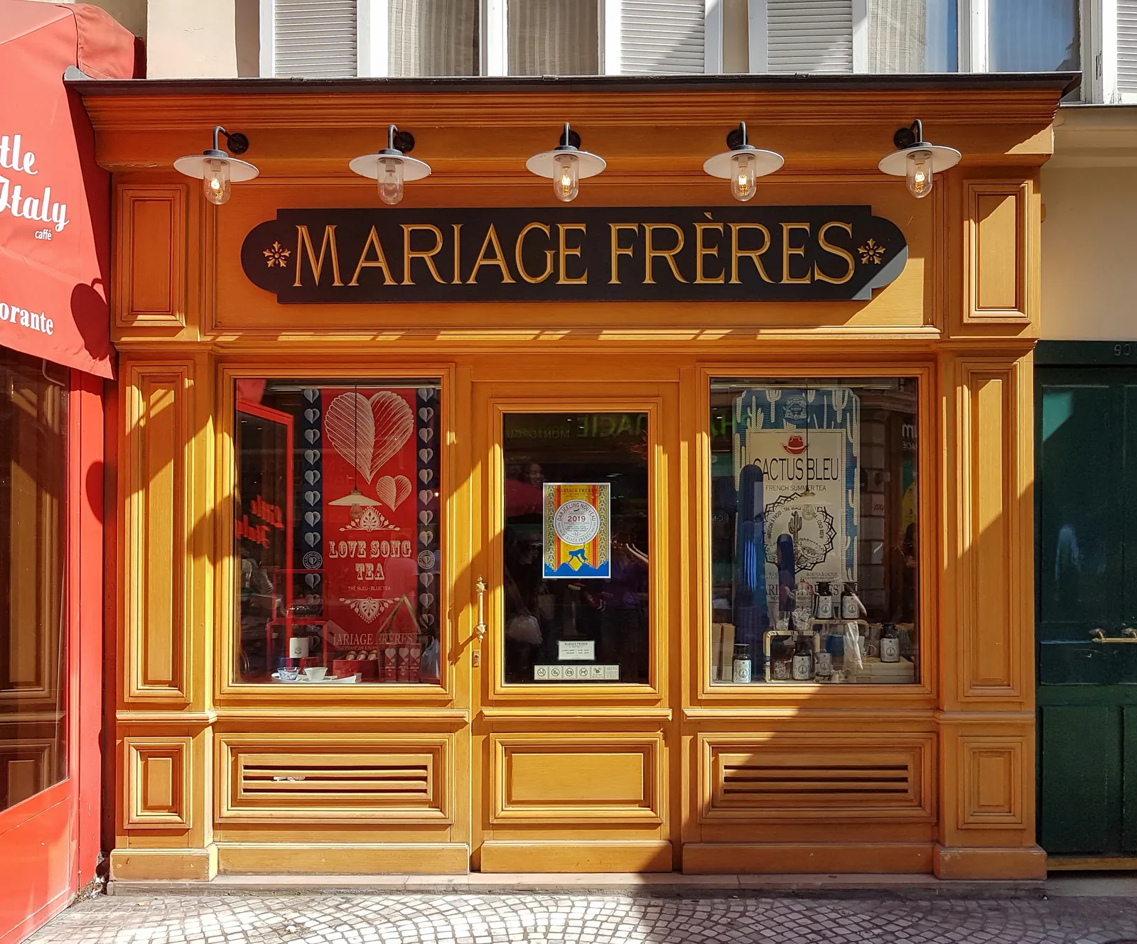 The wooden shopfront of the Mariage Frères counter at 90 rue Montorgueil, with its gold-lettered sign and lamps above the windows.