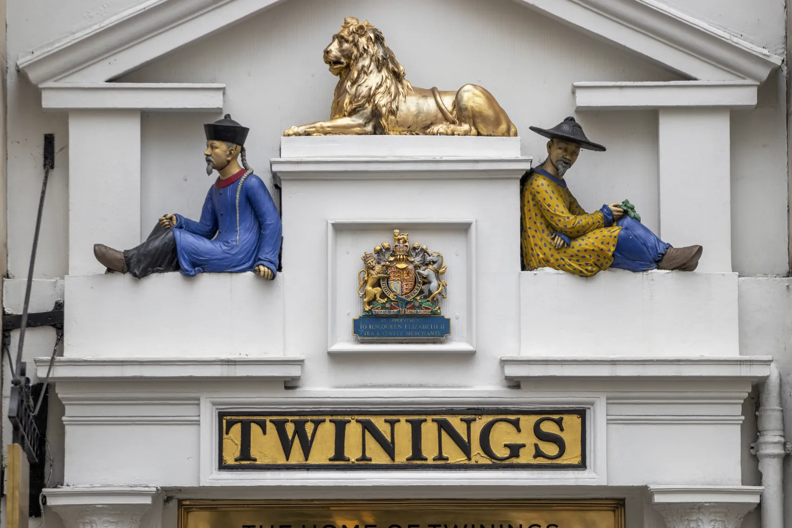 The pediment over the Twinings doorway: a reclining golden lion, two seated Chinese figures and the royal coat of arms above the gold TWININGS sign.