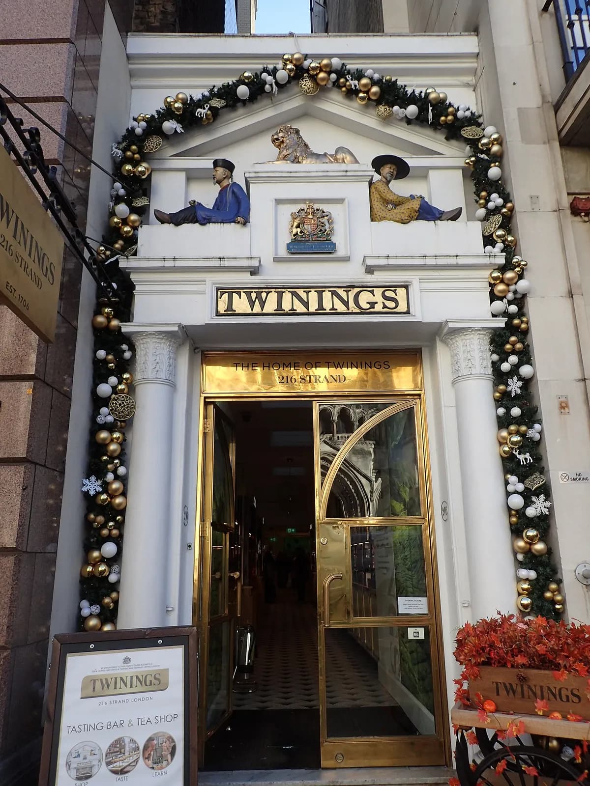The Twinings entrance on the Strand dressed with a gold and white Christmas garland, with a 'Tasting Bar & Tea Shop' board by the door.
