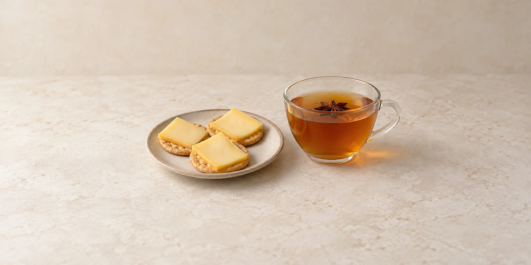 Young Gouda on crackers beside a cup of amber star anise tea.