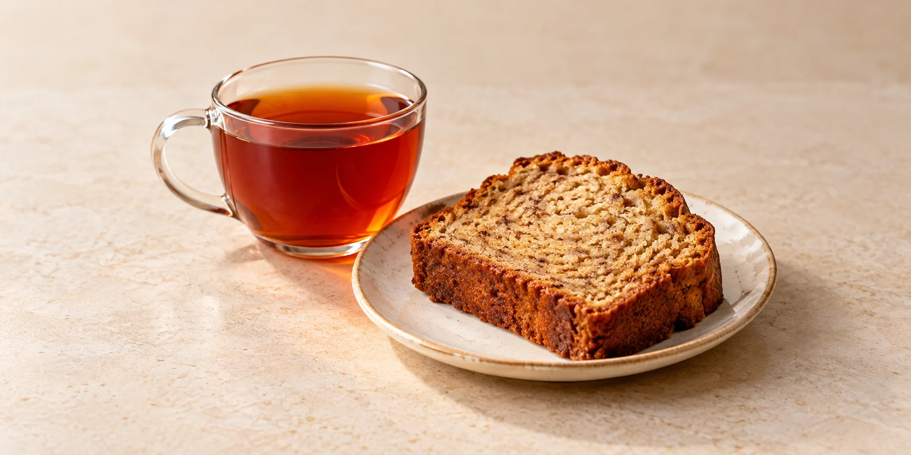 A thick slice of banana bread beside amber-red rooibos tea.