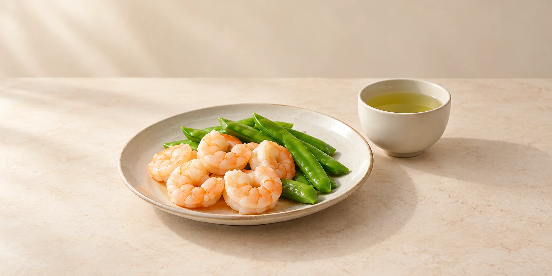 Steamed prawns and snow peas beside a cup of Anji Bai Cha tea.